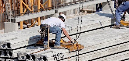 Rückenschmerzen am Bau: Handwerker hebt eine schwere Last
