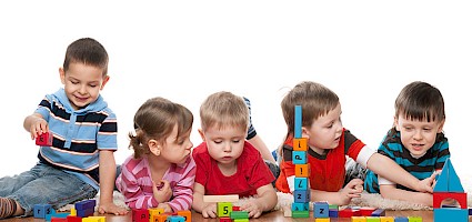 Kinder spielen mit Bauklötzen und bauen kleine Eigenheime