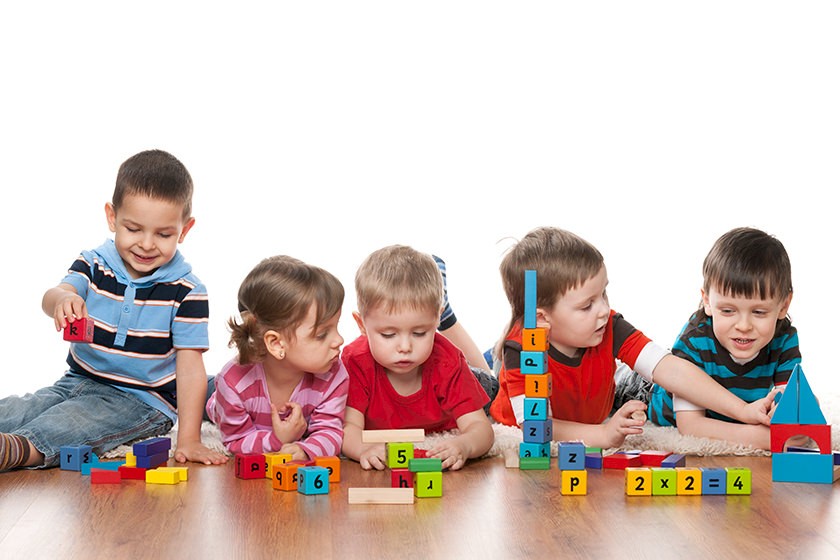 Kinder spielen mit Bauklötzen und bauen kleine Eigenheime