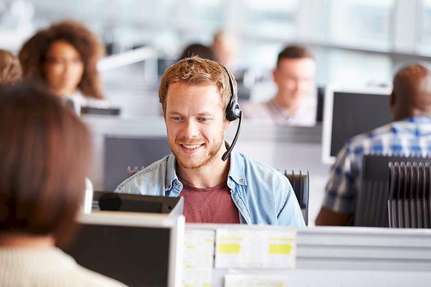 Mitarbeiter aus der Telefonrecherche telefoniert über ein Headset und sammelt neue Informationen zu Bauprojekten.