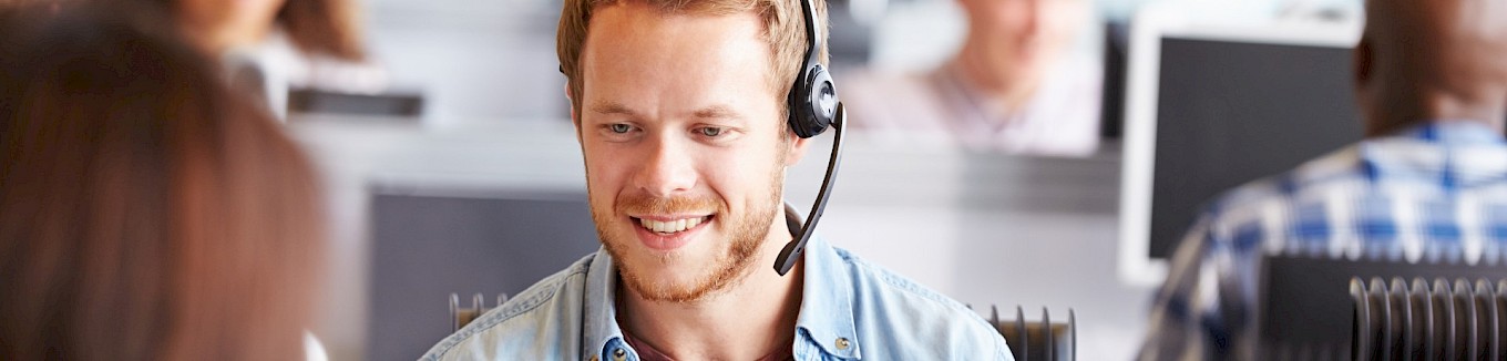 Mitarbeiter aus der Telefonrecherche telefoniert über ein Headset und sammelt neue Informationen zu Bauprojekten.