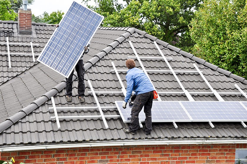 Solarpflicht: Monteure installieren Solaranlage auf Hausdach.