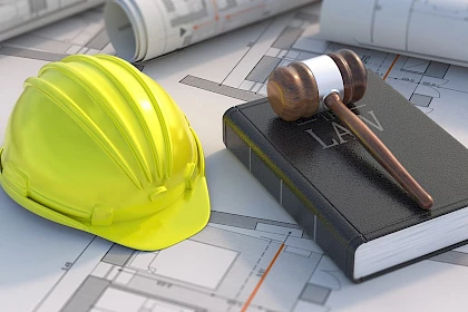 Modulbauweise: Schutzhelm neben Gesetzbuch mit Hammer