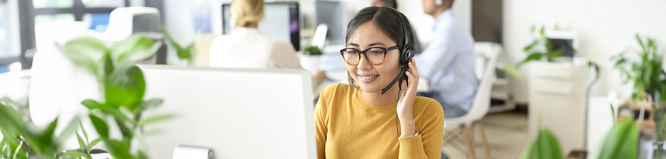 Kundenservice Mitarbeiterin telefoniert lächelnd mit Kund:innen